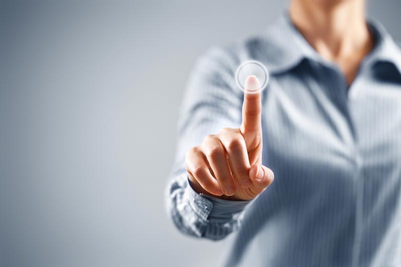 Close-up of a woman's hand pressing a transparent button, representing engagement with tech for older adults