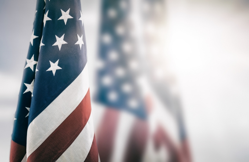 Close-up of three American flags, with the two in the background softly focused, symbolizing Memorial Day and honoring fallen soldiers.