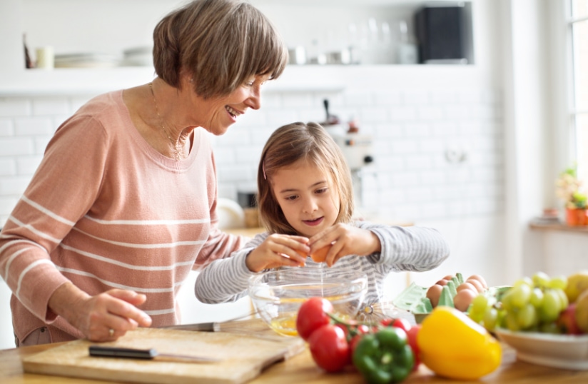 A grandmother and her granddaughter cooking together, highlighting the tradition of sharing family recipes as part of creating a legacy cookbook.